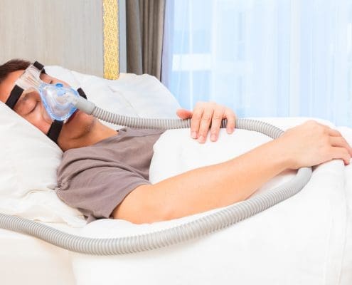 asian-man-wearing-cpap-mask-connecting-to-air-hose-sleeping-on