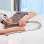 asian-man-wearing-cpap-mask-connecting-to-air-hose-sleeping-on