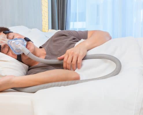 asian-man-wearing-cpap-mask-connecting-to-air-hose-sleeping-on