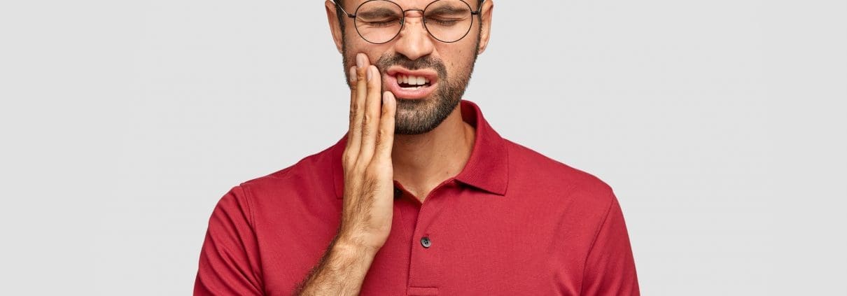 photo-of-caucasian-man-suffers-painful-toothache-has-rotten-tooth-needs-to-visit-dentist-keeps-eyes-closed-from-pain-dressed-in-casual-red-t-shirt-isolated-over-white-background-touches-cheek