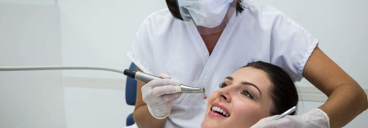 dentist-examining-a-female-patient-with-tools-at-dental-clinic