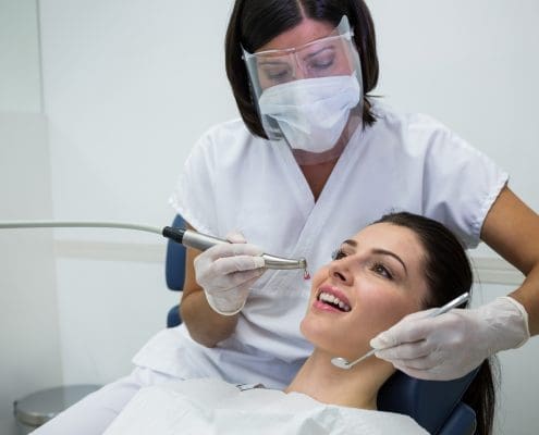 dentist-examining-a-female-patient-with-tools-at-dental-clinic