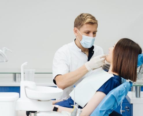 close-up-portrait-beautiful-young-lady-sitting-dental-chair-while-stomatologist-hands-sterile-gloves-holding-tooth-samples